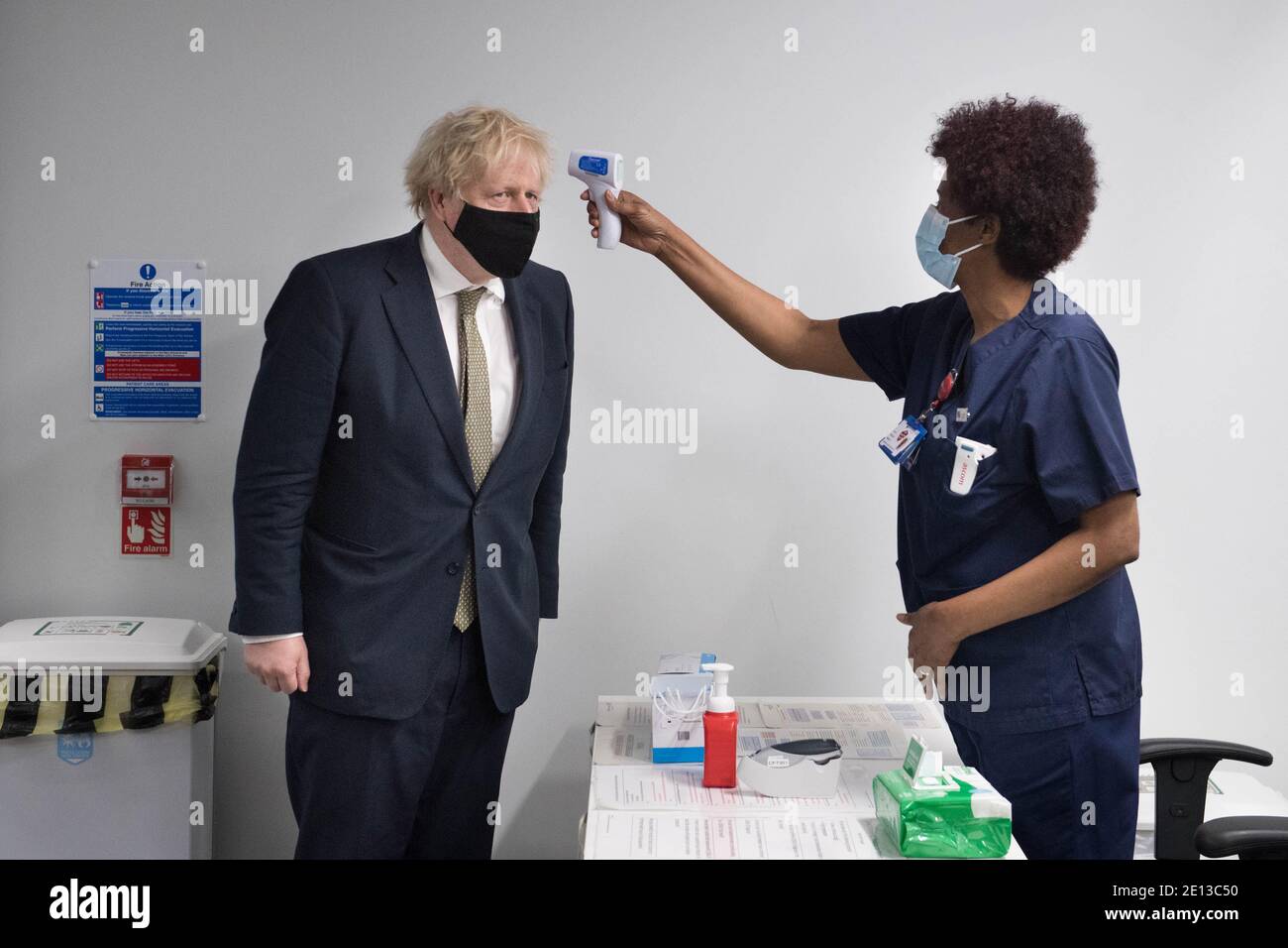 La température du Premier ministre Boris Johnson est vérifiée au cours d'une visite pour voir le programme de vaccination du Chase Farm Hospital, dans le nord de Londres, qui fait partie du Royal Free London NHS Foundation Trust. Le NHS augmente son programme de vaccination avec 530,000 doses du nouveau vaccin Covid-19 d'Oxford/AstraZeneca, qui a été approuvé, et qui peut être mis en place dans tout le Royaume-Uni. Banque D'Images