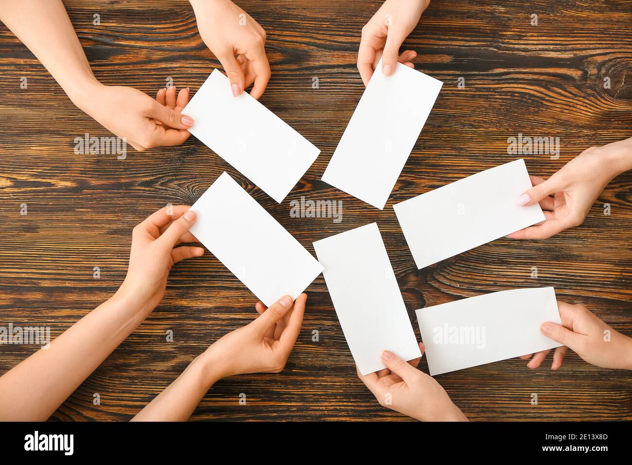 Les gens mains avec des papiers vierges sur fond en bois Banque D'Images