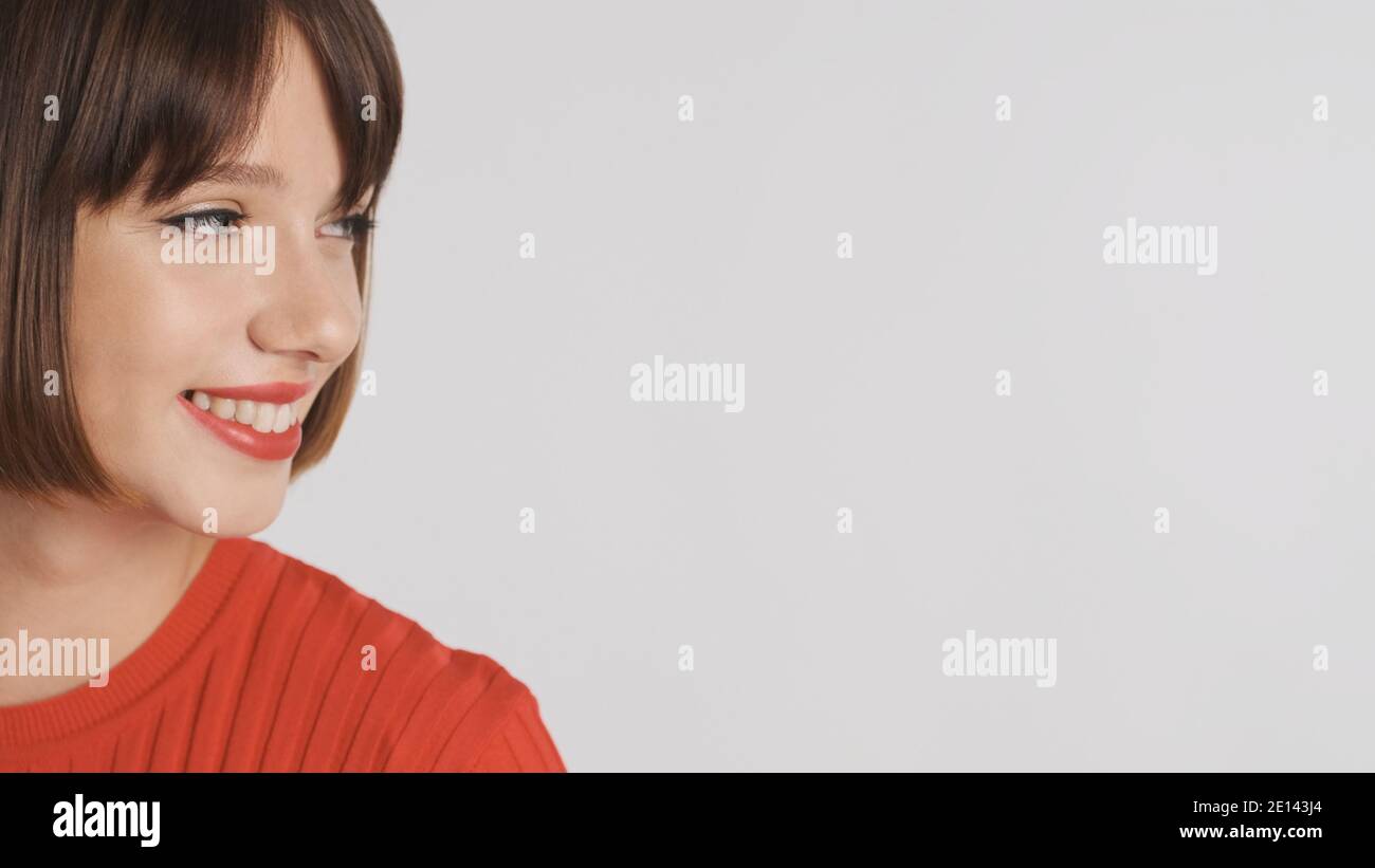 Gros plan jolie brune fille avec des lèvres rouges regardant place pour la publicité ou le texte promotionnel et sourire sur blanc arrière-plan Banque D'Images