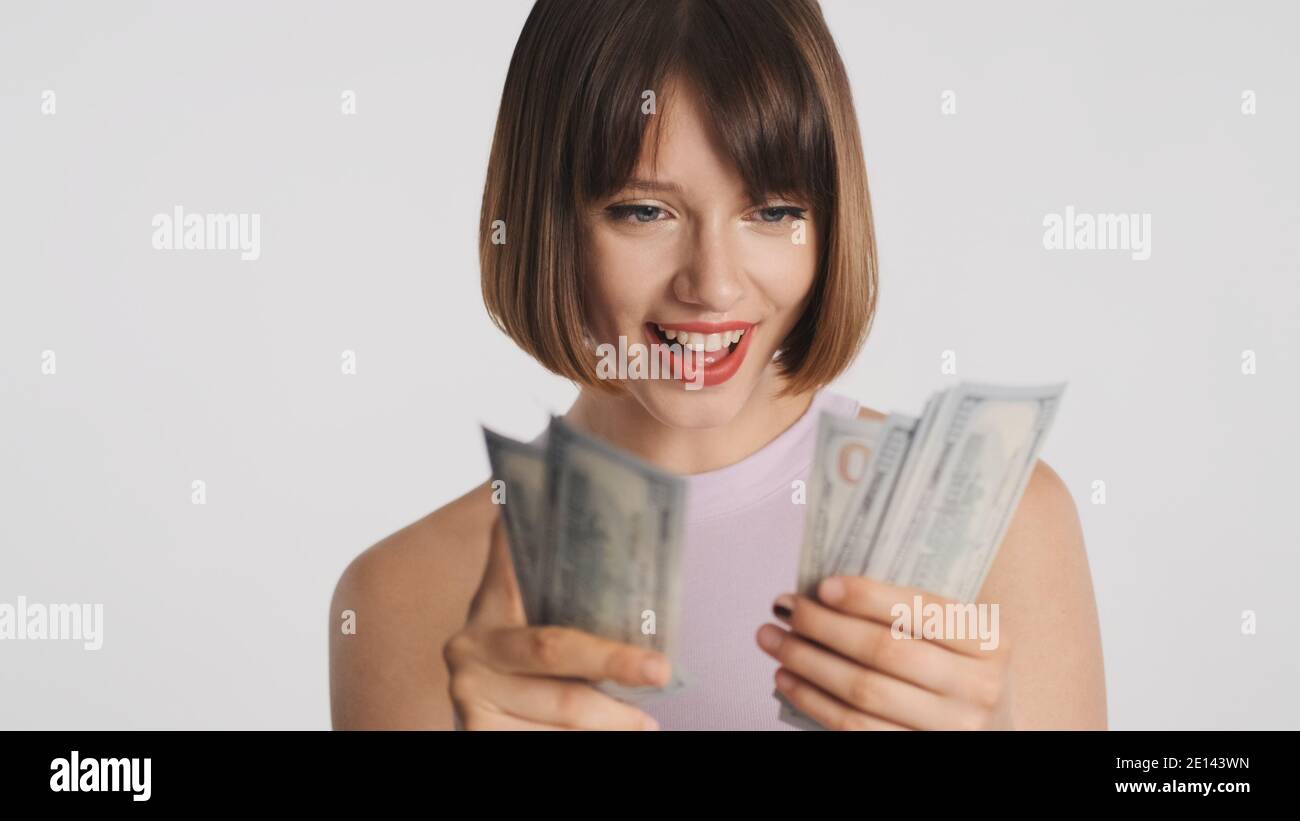 Portrait de gaie brune fille heureux comptant l'argent isolé sur fond blanc. Concept réussi Banque D'Images