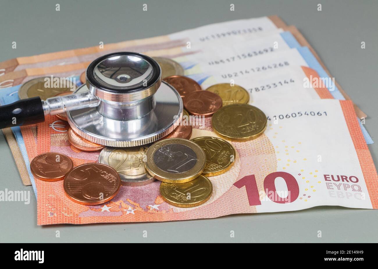 Stéthoscope noir mis sur les pièces et les billets en euros pour symboliser le coût des soins de santé Banque D'Images