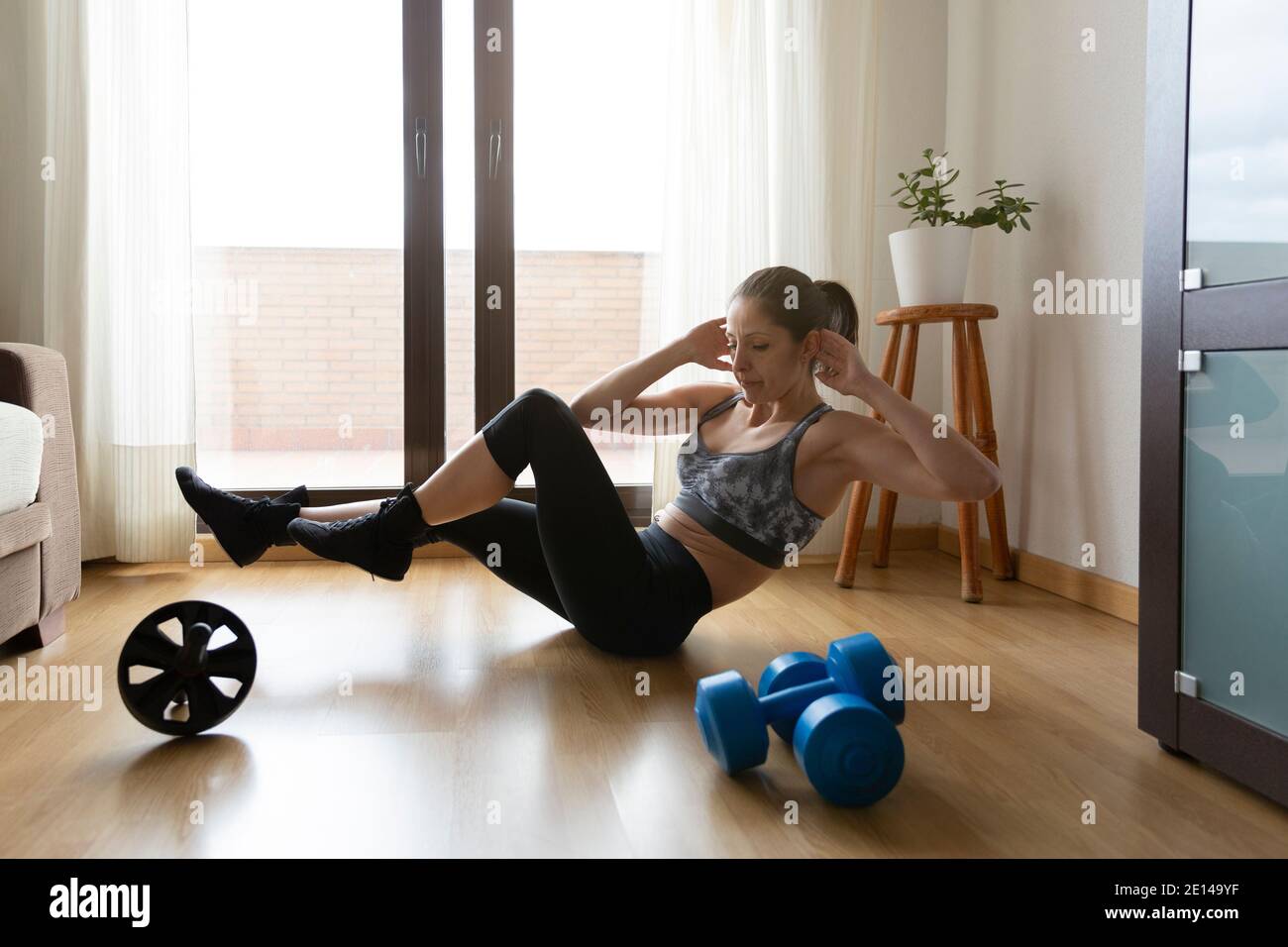 Fitness fille faisant des exercices abdominaux à la maison. Concept du sport, de la santé et du bien-être. Espace pour le texte. Banque D'Images
