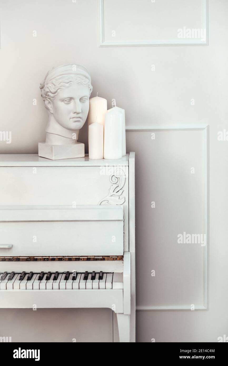 Piano blanc avec couvercle ouvert sur fond blanc. Statue de gypse blanc. Intérieur blanc Banque D'Images