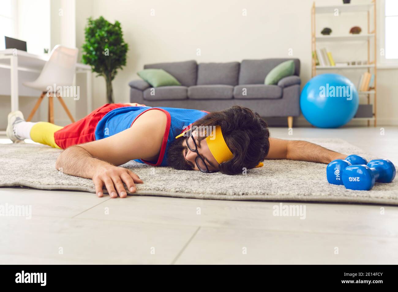 Jeune sportif fatigué et sans motivation couché sur le sol après avoir abandonner entraînement physique avec haltères Banque D'Images