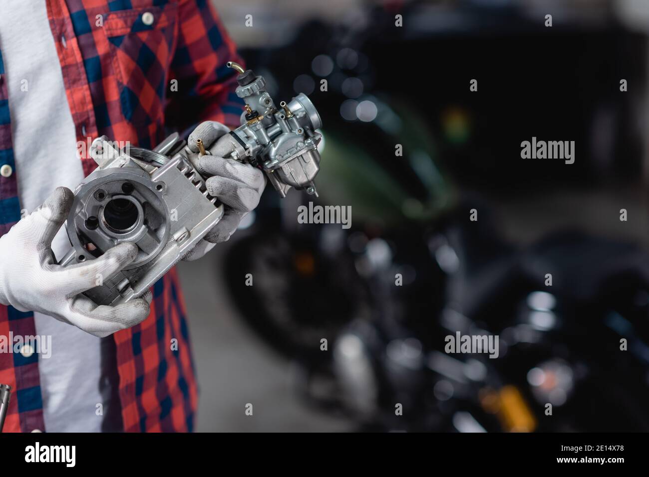vue rognée du mécanicien dans des gants tenant une partie de la moto transmission Banque D'Images