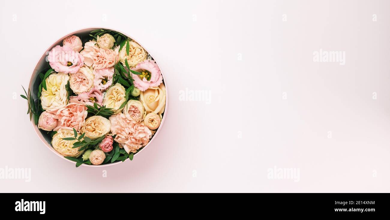 Luxe belles fleurs dans un chapeau rond boîte sur le fond rose avec espace de copie. Cadeau ou cadeau le jour de la Saint-Valentin, 8 mars, fête des mères Banque D'Images