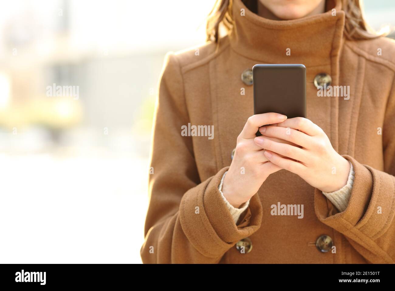 Vue avant gros plan des mains d'une femme à l'aide d'un smartphone marche dans la rue en hiver Banque D'Images