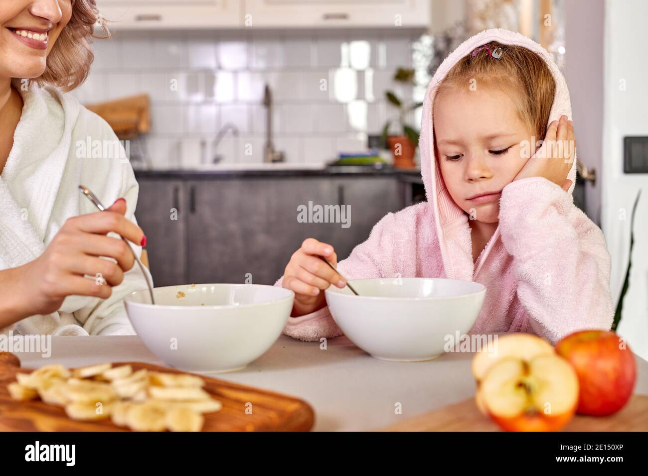 l'enfant fille ne veut pas manger le petit déjeuner, s'asseoir derrière la  table veulent dormir, dans la cuisine moderne claire le matin Photo Stock -  Alamy