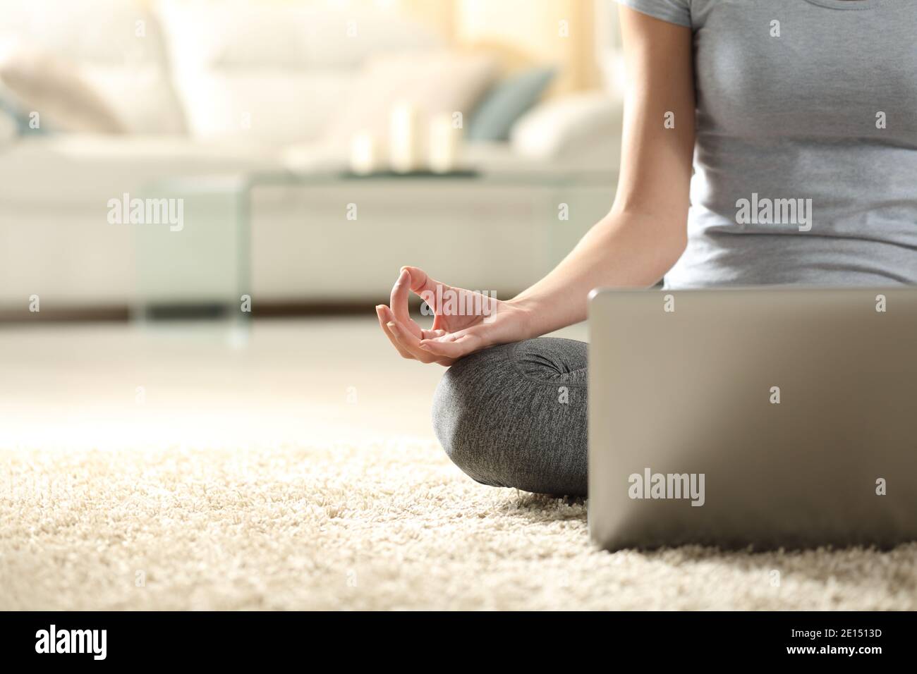 Vue de face gros plan portrait d'une main féminine faisant exercice de yoga regarder le tutoriel sur ordinateur portable sur le sol à accueil Banque D'Images