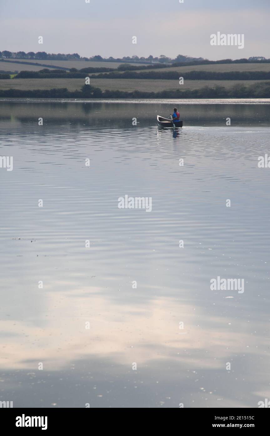Une jeune dame pagayer un canot canadien dans une eau calme Un estuaire de Cornouailles Banque D'Images