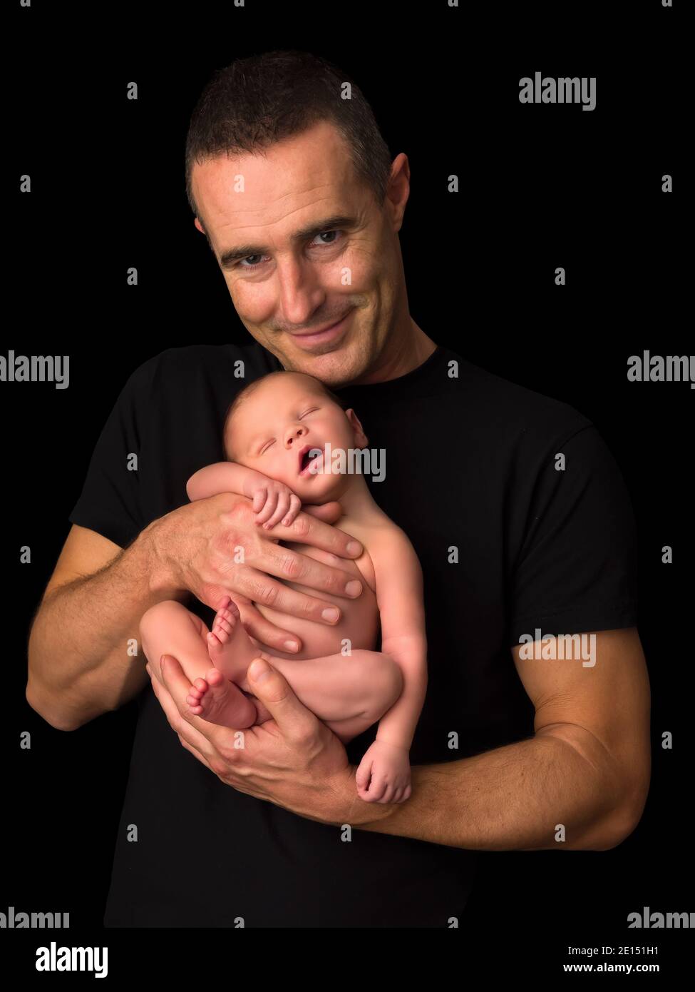 Jeune père tenant son bébé de 7 jours sur fond noir Banque D'Images