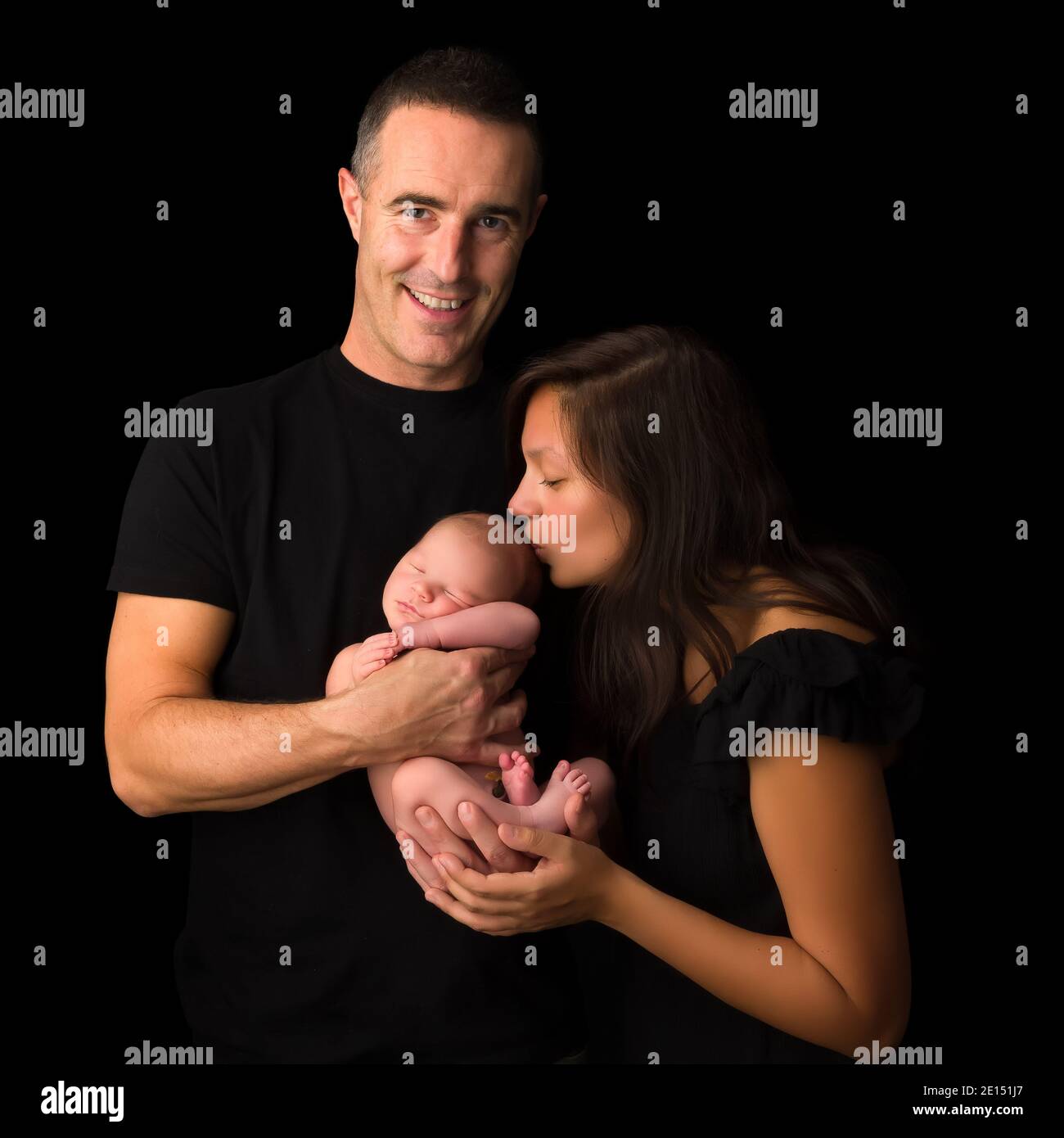 Jeunes parents posant avec leur nouveau-né de 7 jours garçon sur fond noir Banque D'Images