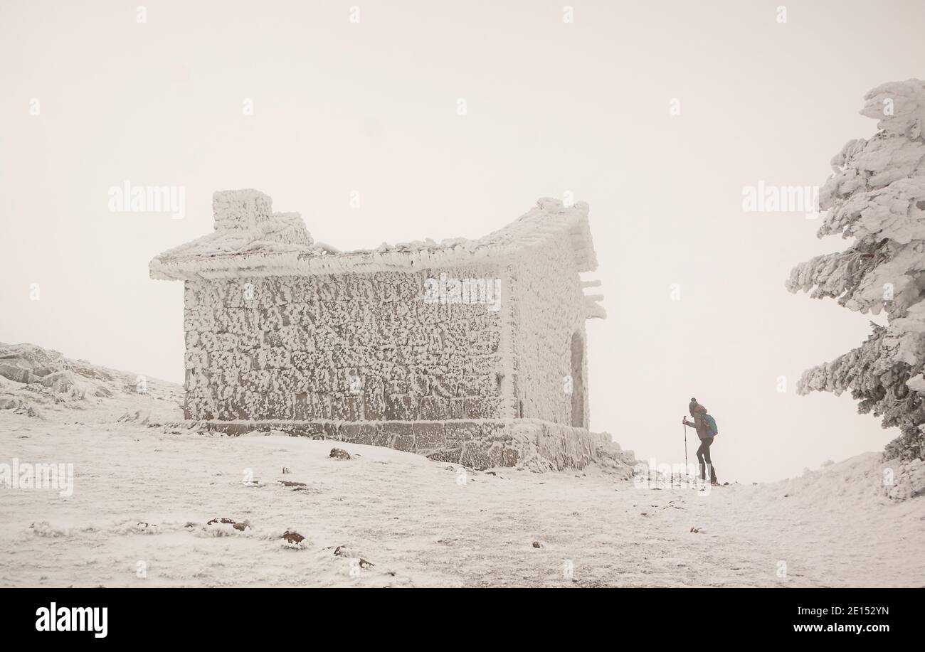 Femme avec des raquettes entrant dans une cabane de montagne. Tempête de neige par temps extrême. Dans le parc national de la Sierra de Guadarrama Banque D'Images
