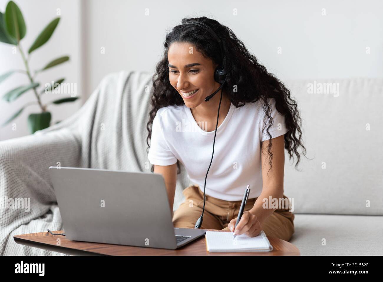 Jeune femme joyeuse étudiant en ligne, en utilisant un ordinateur portable à la maison Banque D'Images