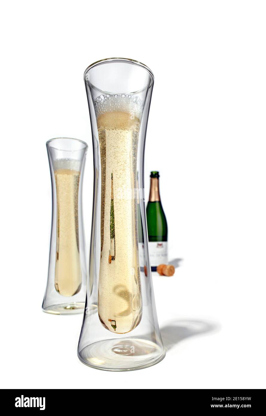 Des verres à champagne flottants avec une bouteille de champagne ouverte sont photographiés un arrière-plan blanc Banque D'Images