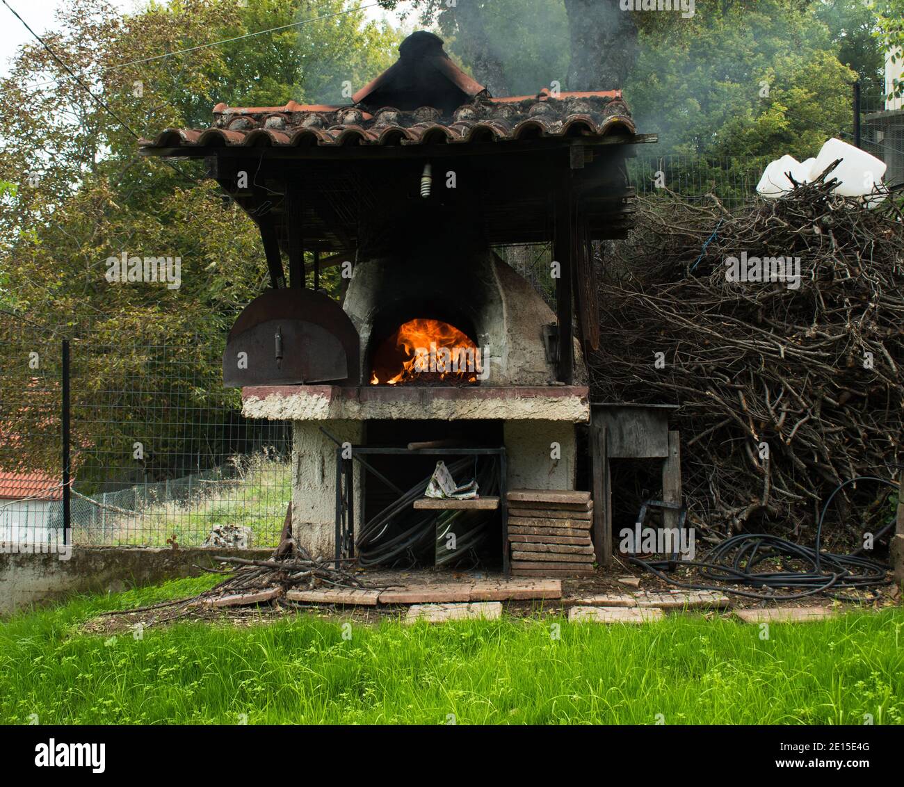 Four à bois externe avec terrain d'herbe verte au premier plan. Four à pizza traditionnel à bois. Flamme dans le four. Banque D'Images Four à bois externe avec terrain d'herbe verte au premier plan. Four à pizza traditionnel à bois. Flamme dans le four. Banque D'Images