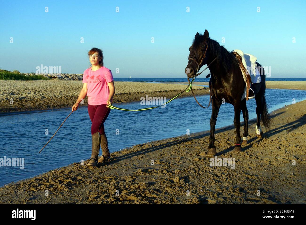 Femme cheval rivière femme marchant le long de la rivière va à la mer marcher un cheval Banque D'Images