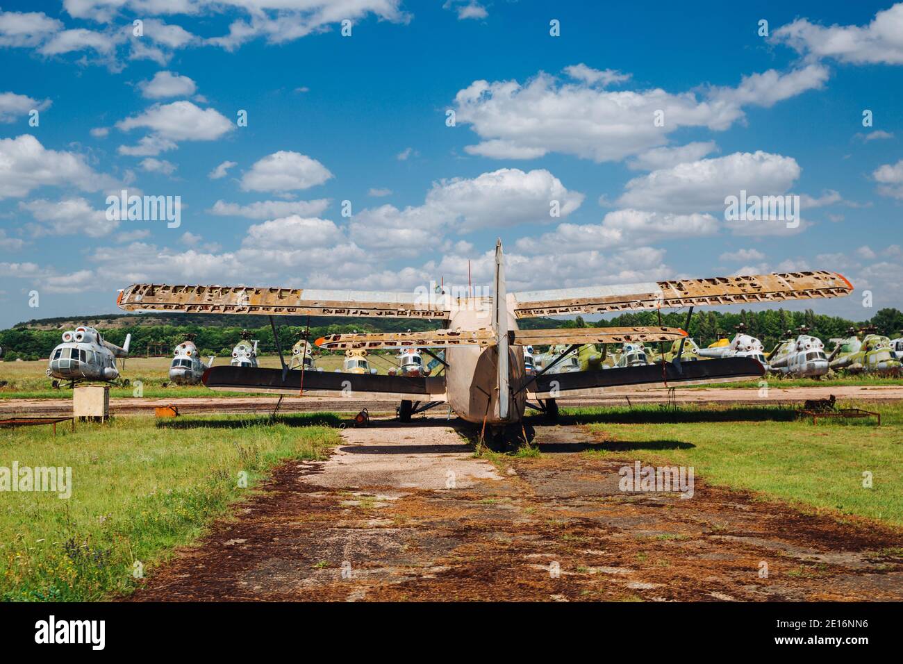 Un vieux avion abandonné, détruit et rouillé se trouve sur l'herbe sous un ciel bleu avec des nuages blancs. Banque D'Images