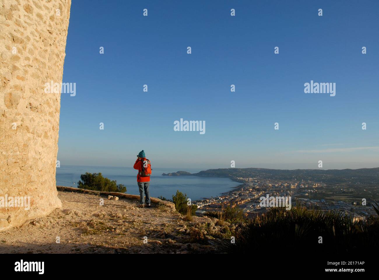 Femme prenant une photo, debout à côté d'un moulin à vent sur le promontoire en regardant Javea et la Costa Blanca, province d'Alicante, Espagne Banque D'Images