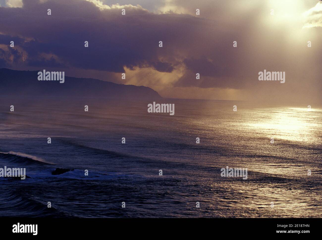 Late afternoon sun on large swell amid rainsqualls seen from heiau over Waimea Bay, North Shore, Oahu, Hawaii Banque D'Images