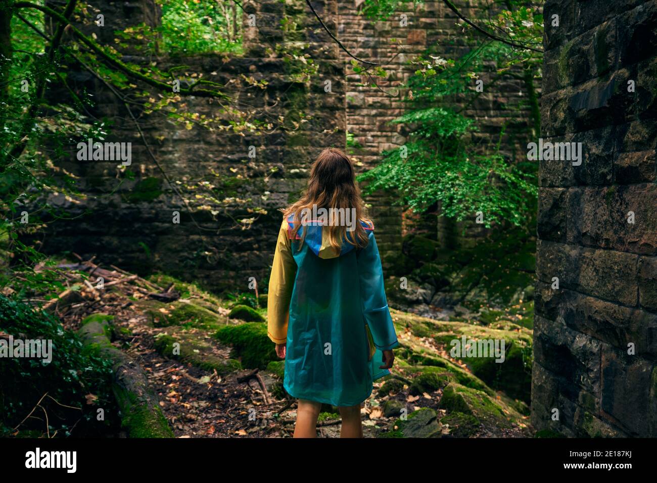 Une jeune femme marche dans la forêt par un mur en pierre Banque D'Images