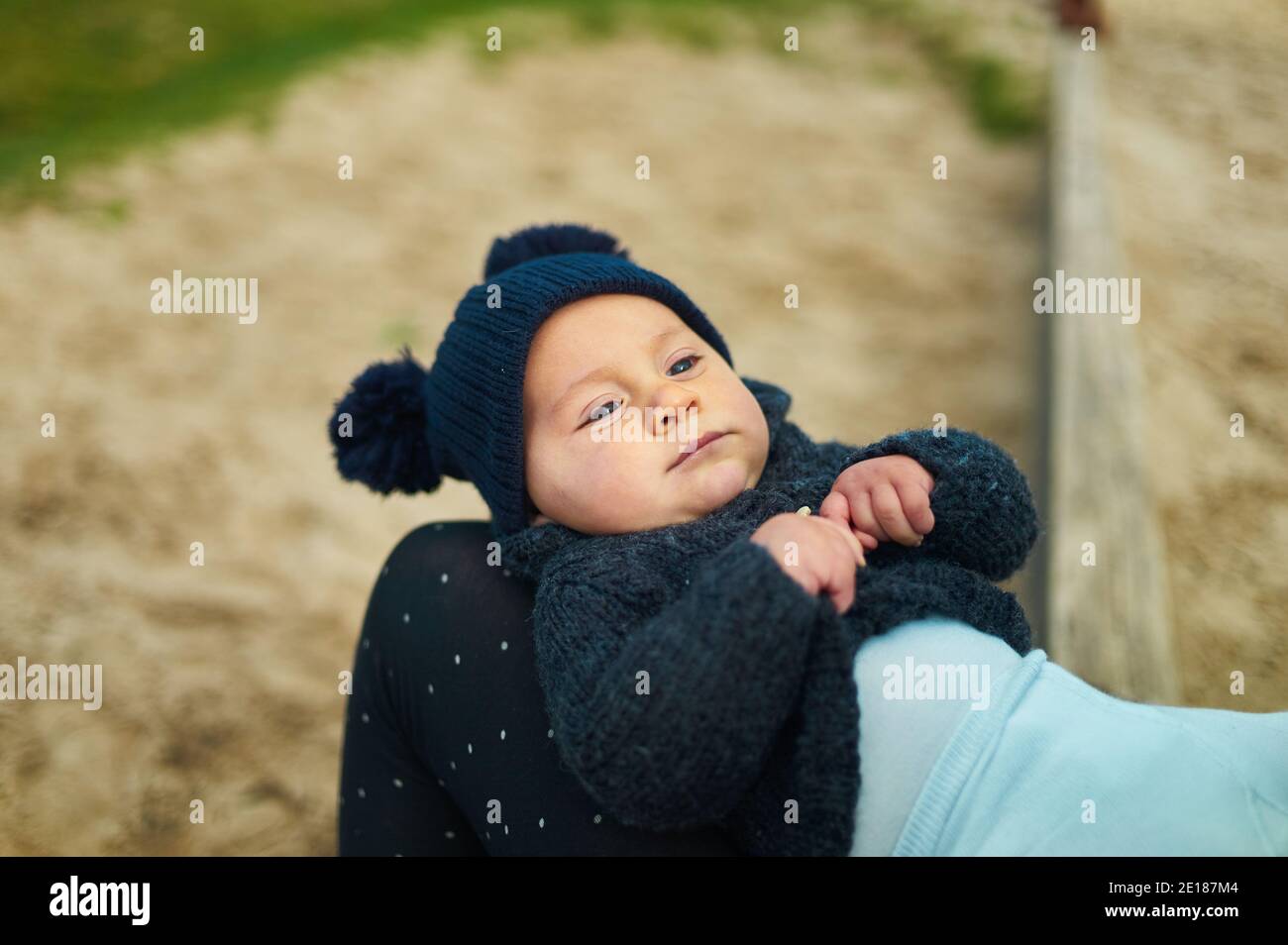 Un petit bébé se repose sur les genoux de ses mères un jour d'automne ensoleillé dans le parc Banque D'Images