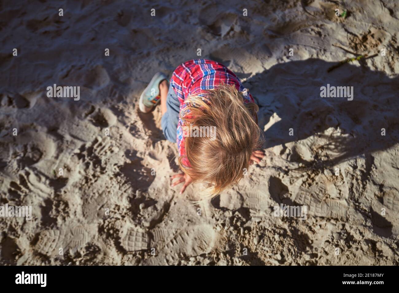 Un petit Preschooler joue dans le sable à un aire de jeux sous le soleil d'automne Banque D'Images