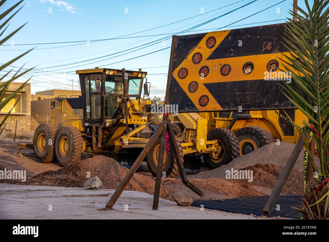 Une grande flèche jaune pointe vers l'équipement de construction de routes en veille tôt le matin à San Carlos, Sonora, Mexique. Banque D'Images