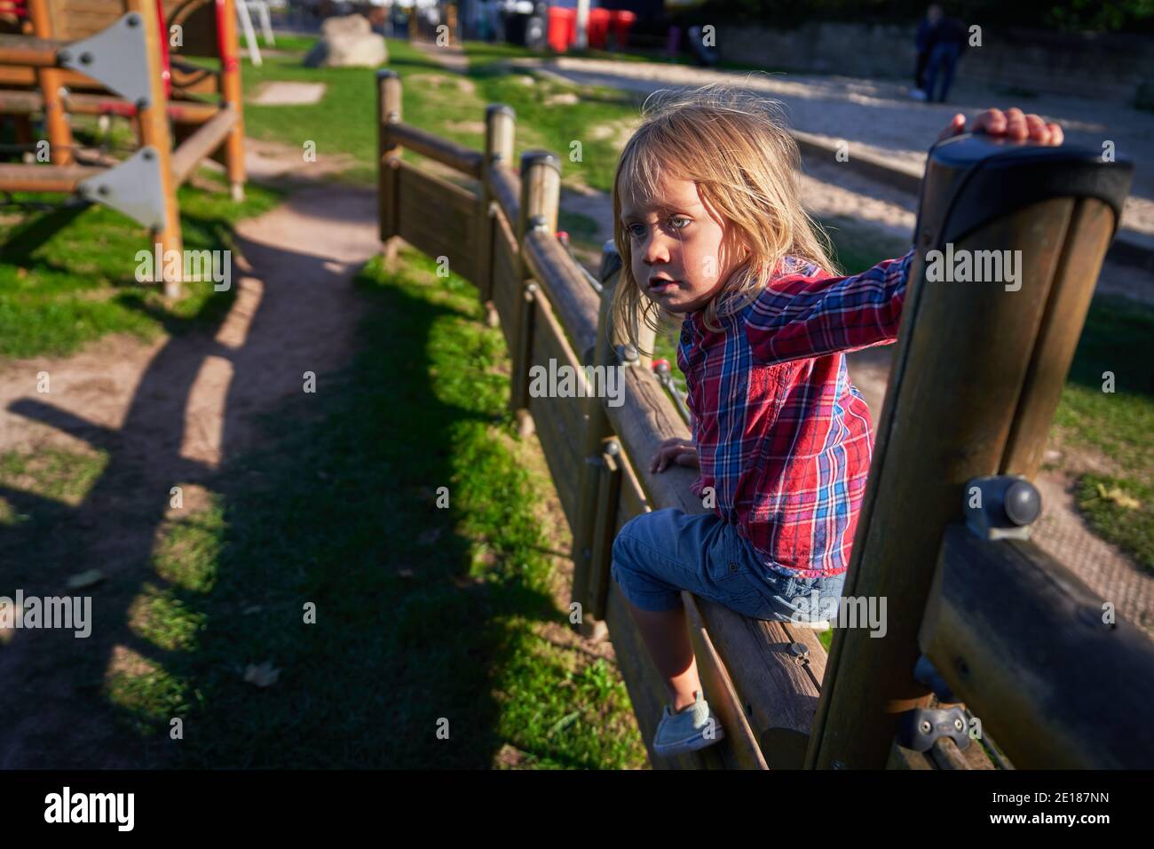 Un petit avant-chooler escalade l'équipement de terrain de jeu dans le parc un jour d'automne ensoleillé Banque D'Images