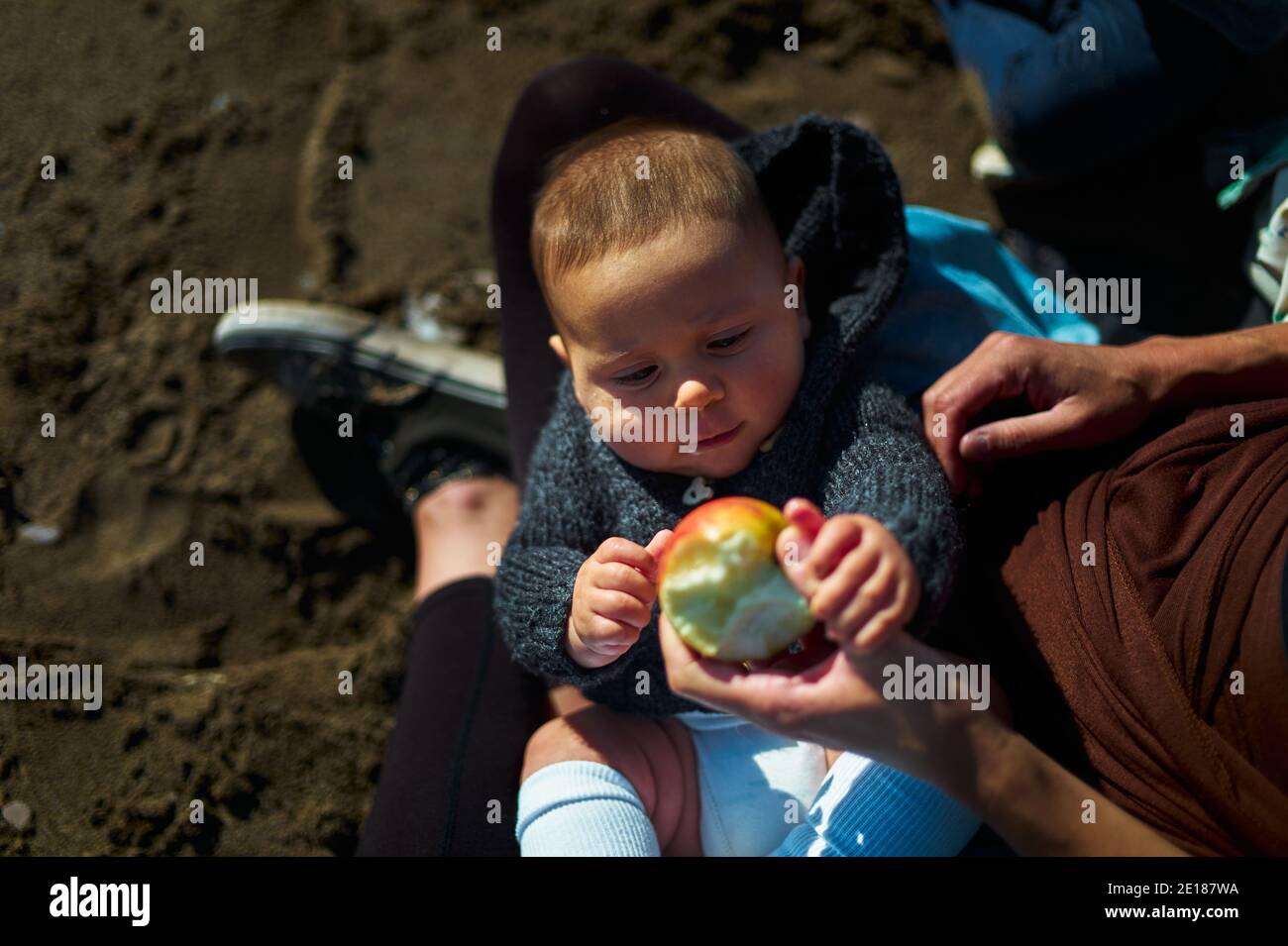 Une jeune mère offre une pomme à son bébé la plage en automne Banque D'Images