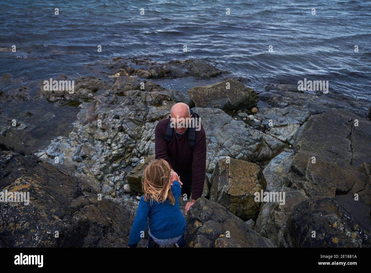 Preschooler jouant avec son grand-père sur la plage rocheuse Banque D'Images