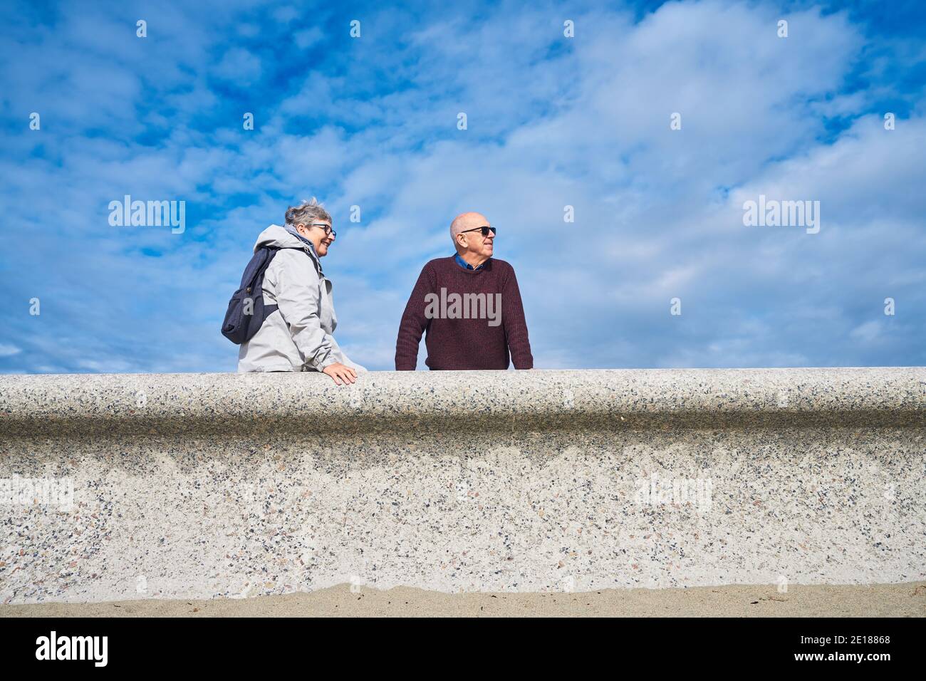 Un couple senior repose sur un mur sur un jour d'automne ensoleillé Banque D'Images