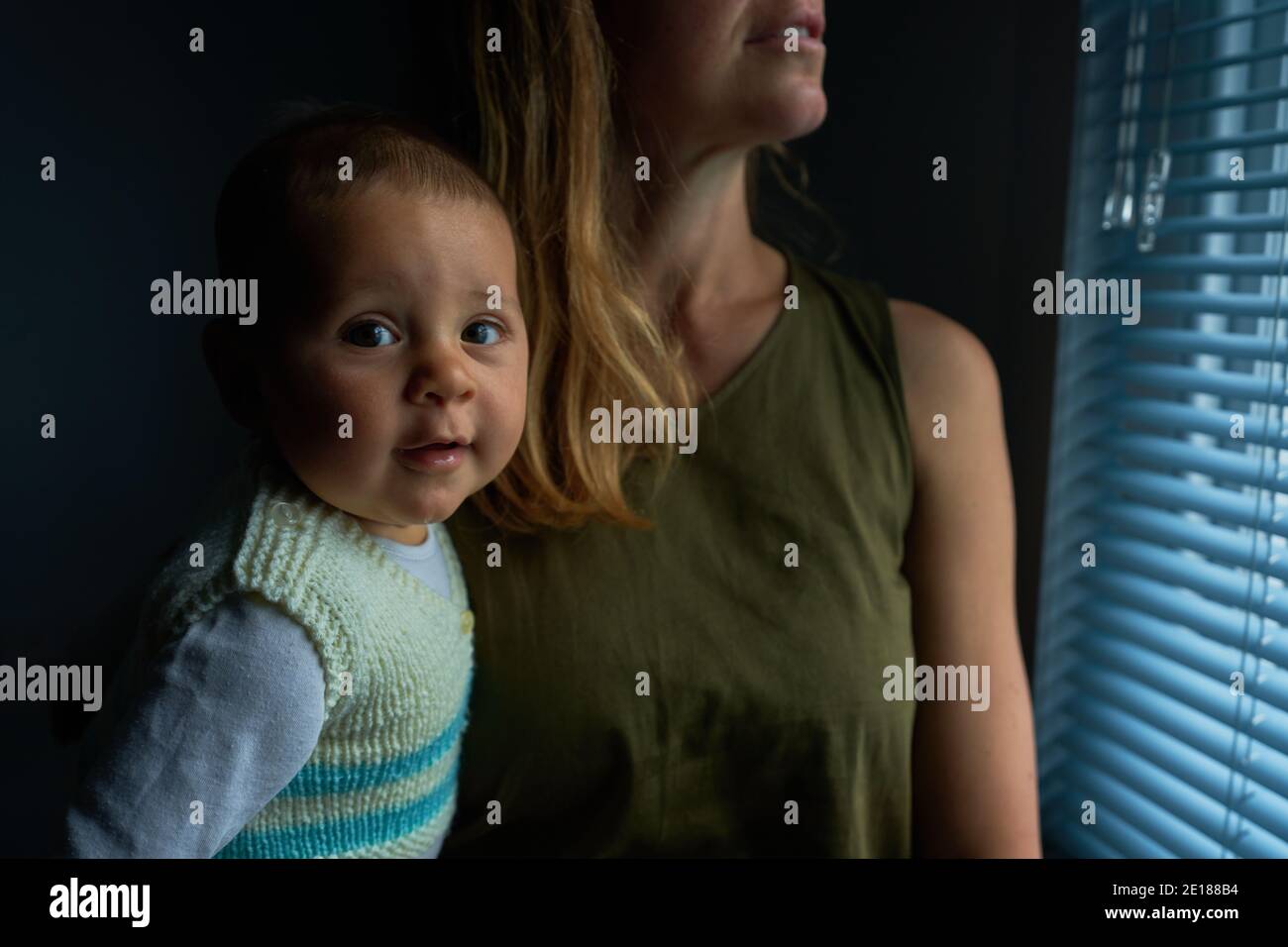Une jeune mère est assise près de la fenêtre avec elle bébé Banque D'Images