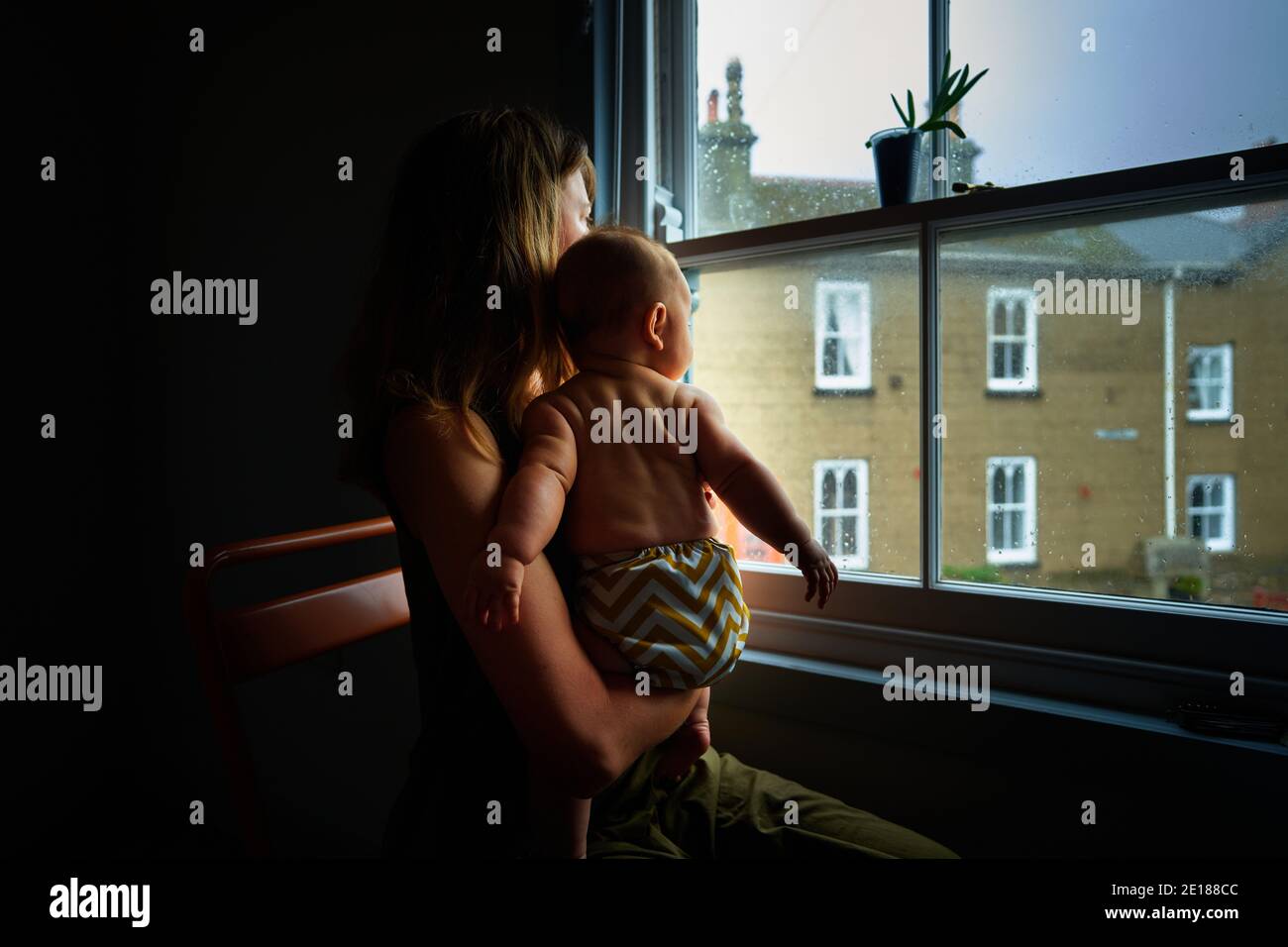 Une jeune mère est assise près de la fenêtre avec elle bébé Banque D'Images