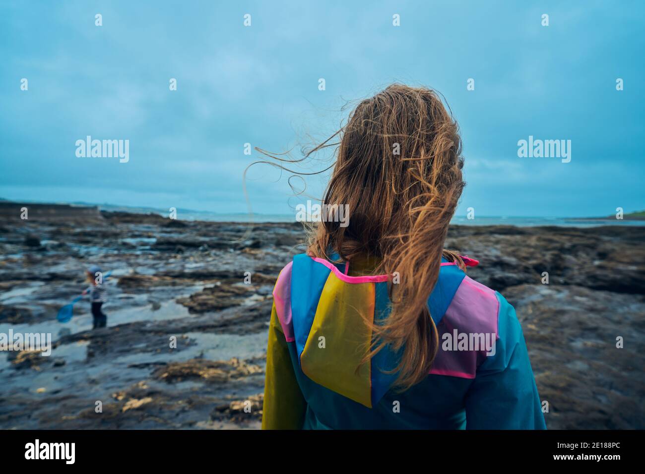 Une jeune femme portant un imperméable est debout près du bord de mer Banque D'Images
