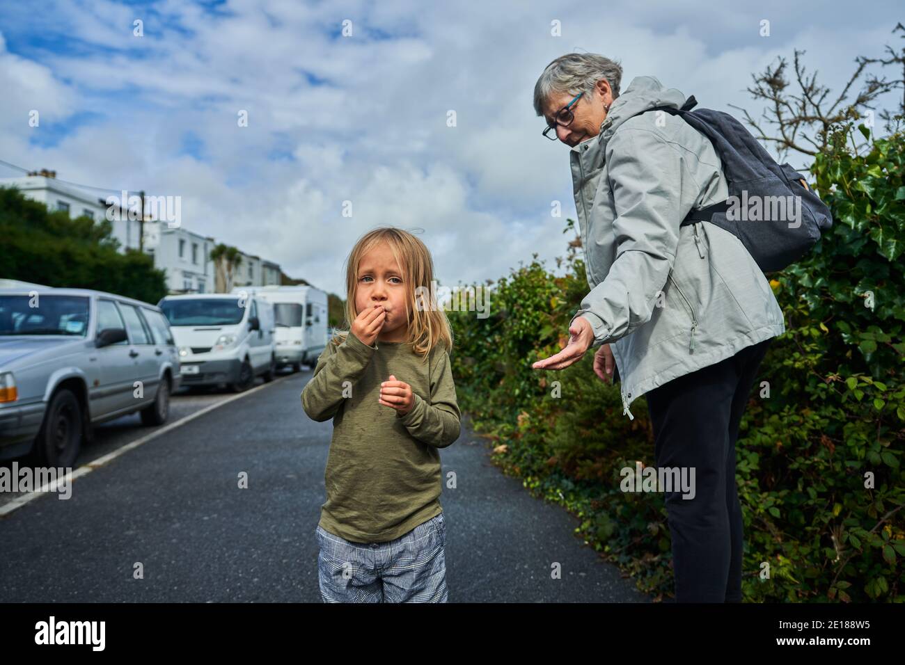 Une grand-mère est de cueillir des beries pour les enfants d'âge préscolaire au bord de la route Banque D'Images