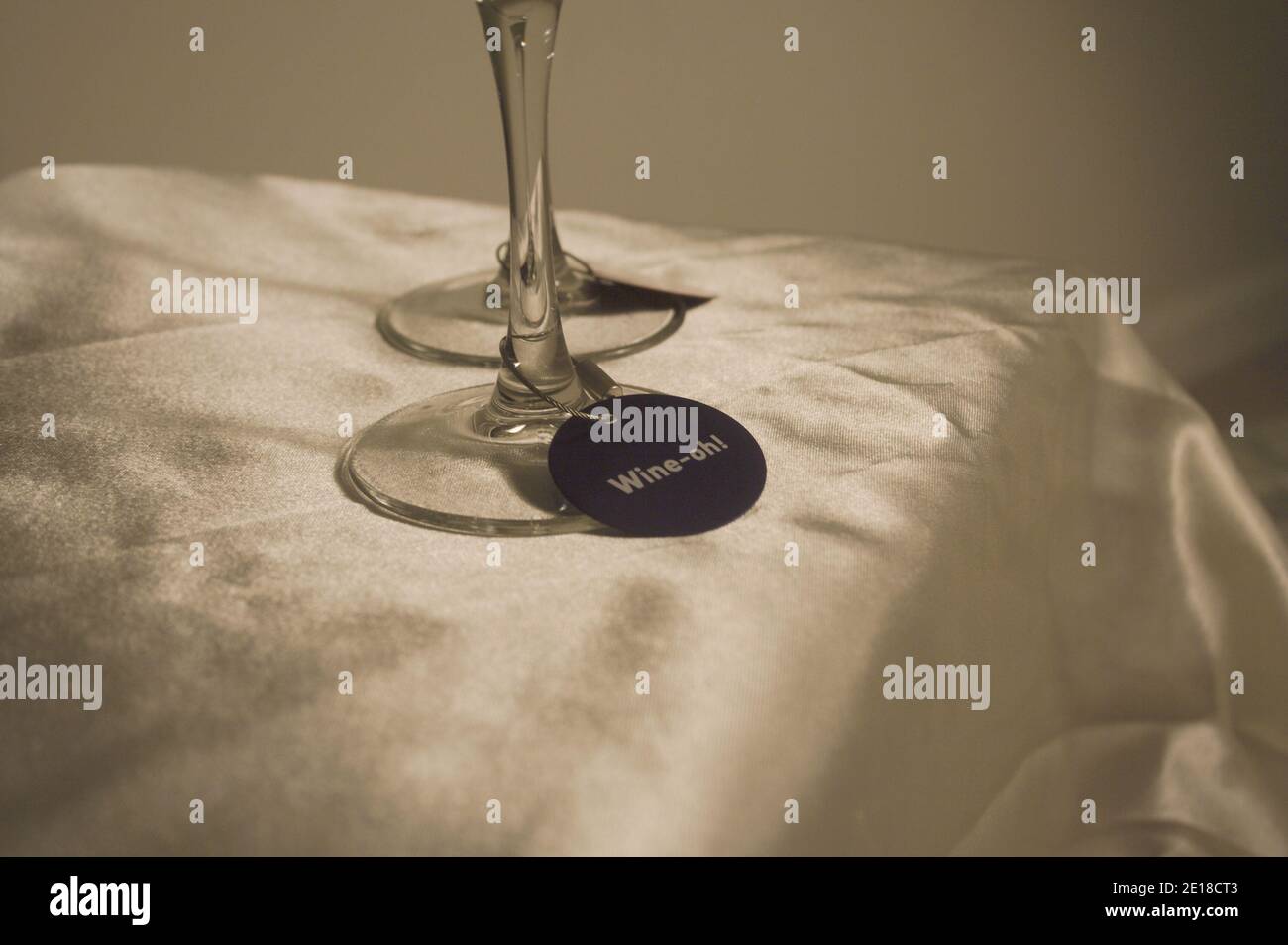 Deux verres à vin sont placés sur une nappe soyeuse or pâle. Chaque verre est doté d'une étiquette d'identification de boisson sur la base. Banque D'Images