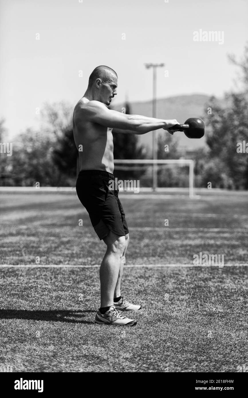 Homme s'entraînant avec Kettle Bell extérieur et muscles flexibles - Exercices de modèle de forme physique musculaire Athletic Body Builder Banque D'Images