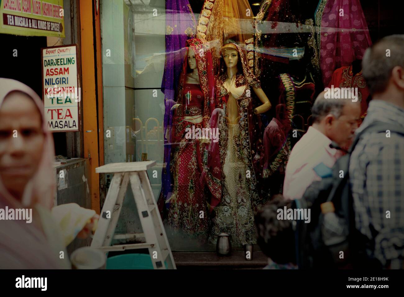 Des gens qui marchent dans une rue, passant une boutique de mode pour femmes côté rue à Varanasi, Uttar Pradesh, Inde. Banque D'Images