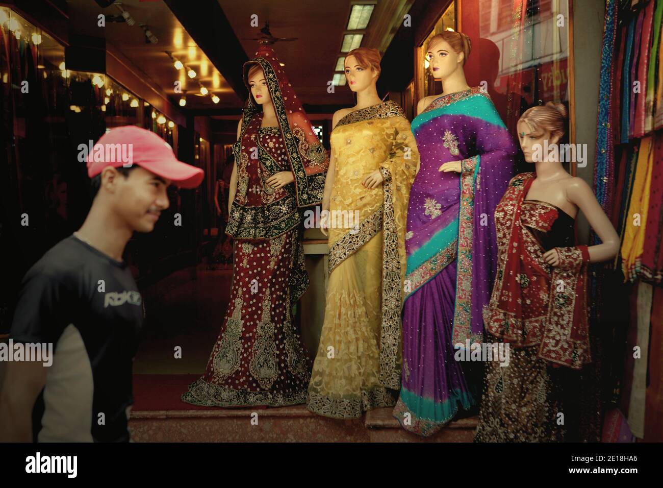 Un homme marchant dans une rue, passant par un quartier commercial où une boutique de mode pour femmes est située à Varanasi, Uttar Pradesh, Inde. Banque D'Images