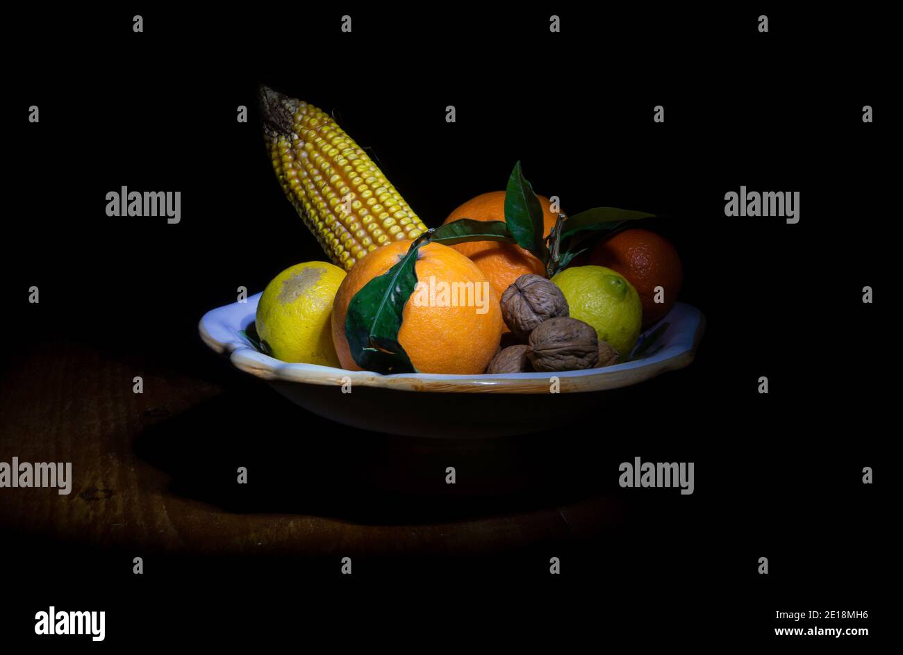 Encore plus de vie avec des fruits d'automne et d'hiver (citrons, mandarines, oranges, noix) et une oreille de maïs dans le style du Caravaggio Banque D'Images