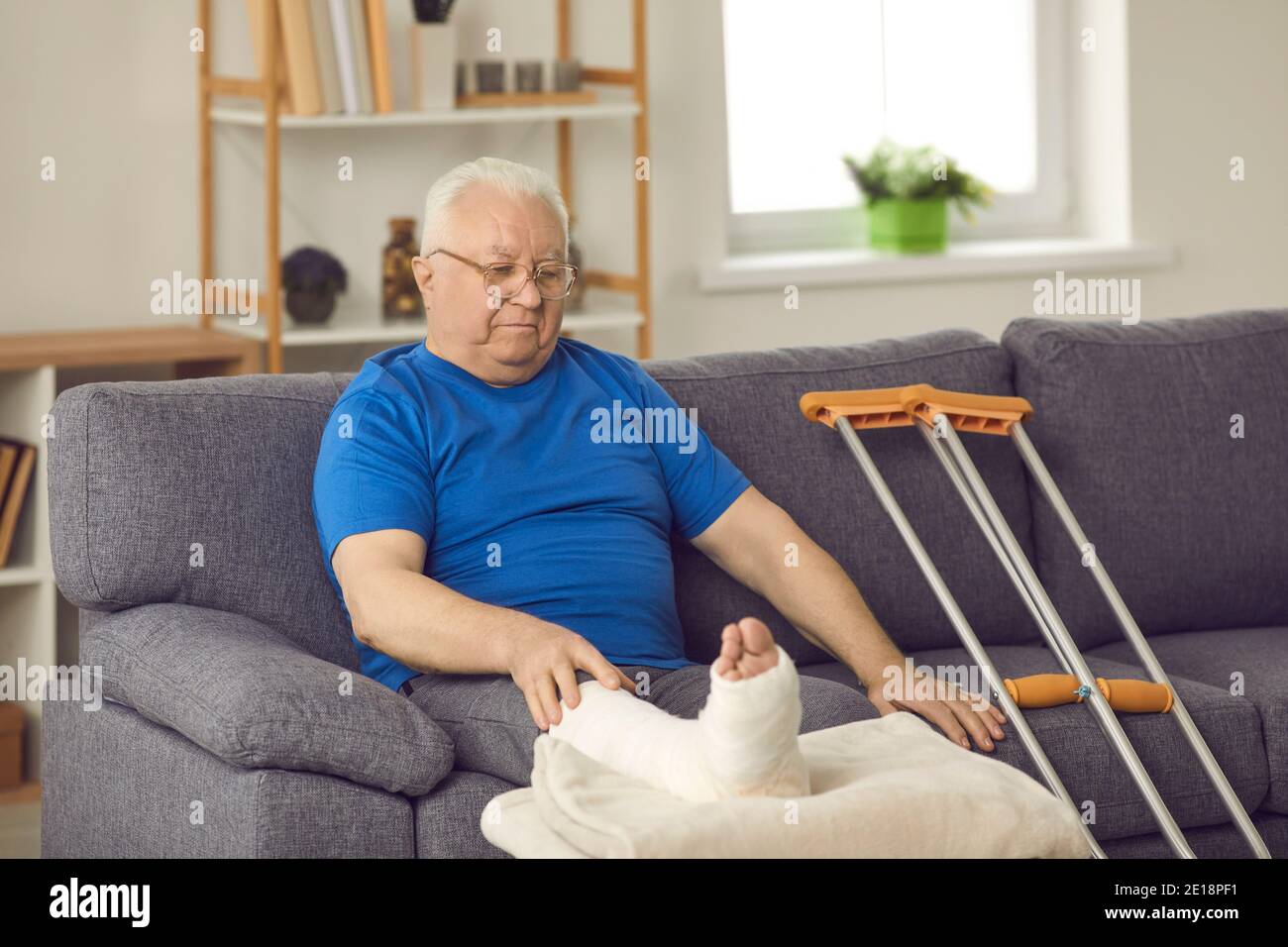 Un homme âgé avec une jambe cassée reste à la maison et attend pour sa fracture osseuse à guérir Banque D'Images