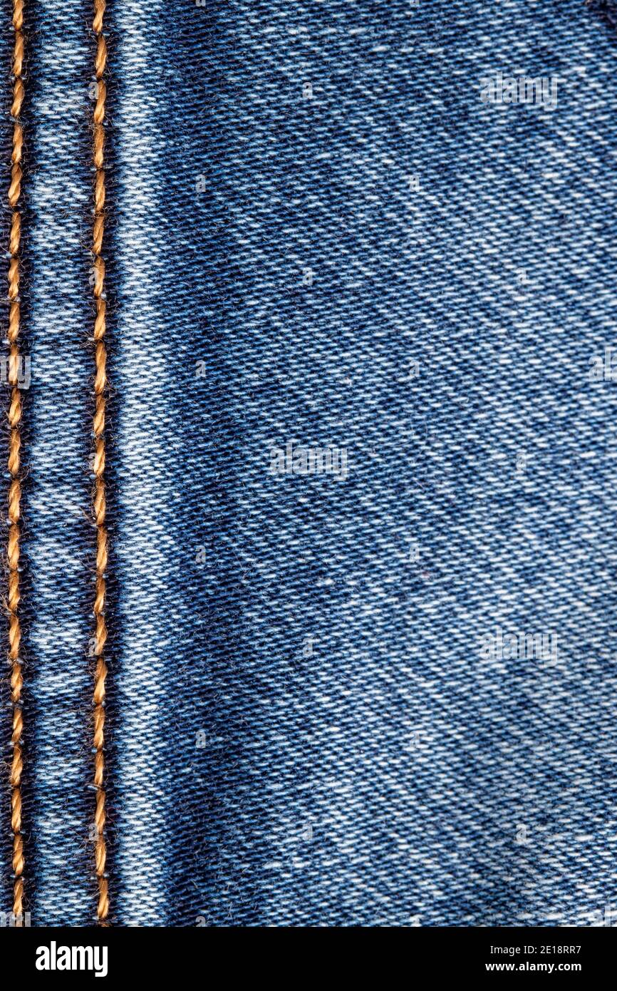 Texture d'arrière-plan du denim. Gros plan sur la surface vide du Jean bleu avec double couture verticale dorée à filetage à gauche. Joint de filetage double macro Banque D'Images