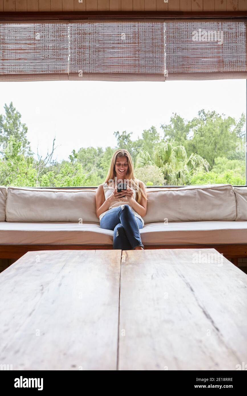 Femme de taille moyenne souriante utilisant un smartphone Banque D'Images