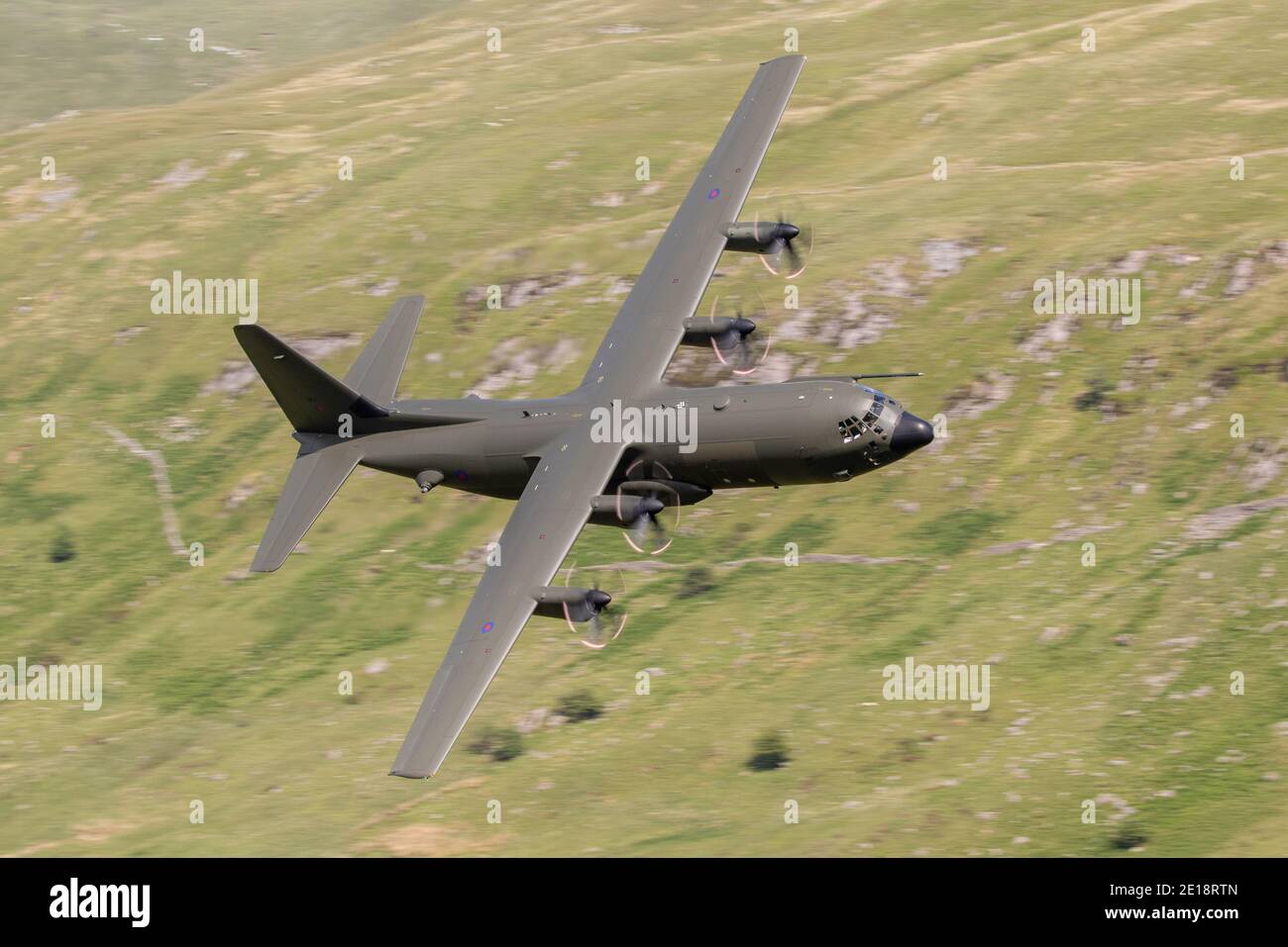 Lockheed C-130 Hercules volant de bas niveau dans les vallées et les montagnes. Transporteur de troupes et de marchandises à motif camouflage vert. Banque D'Images