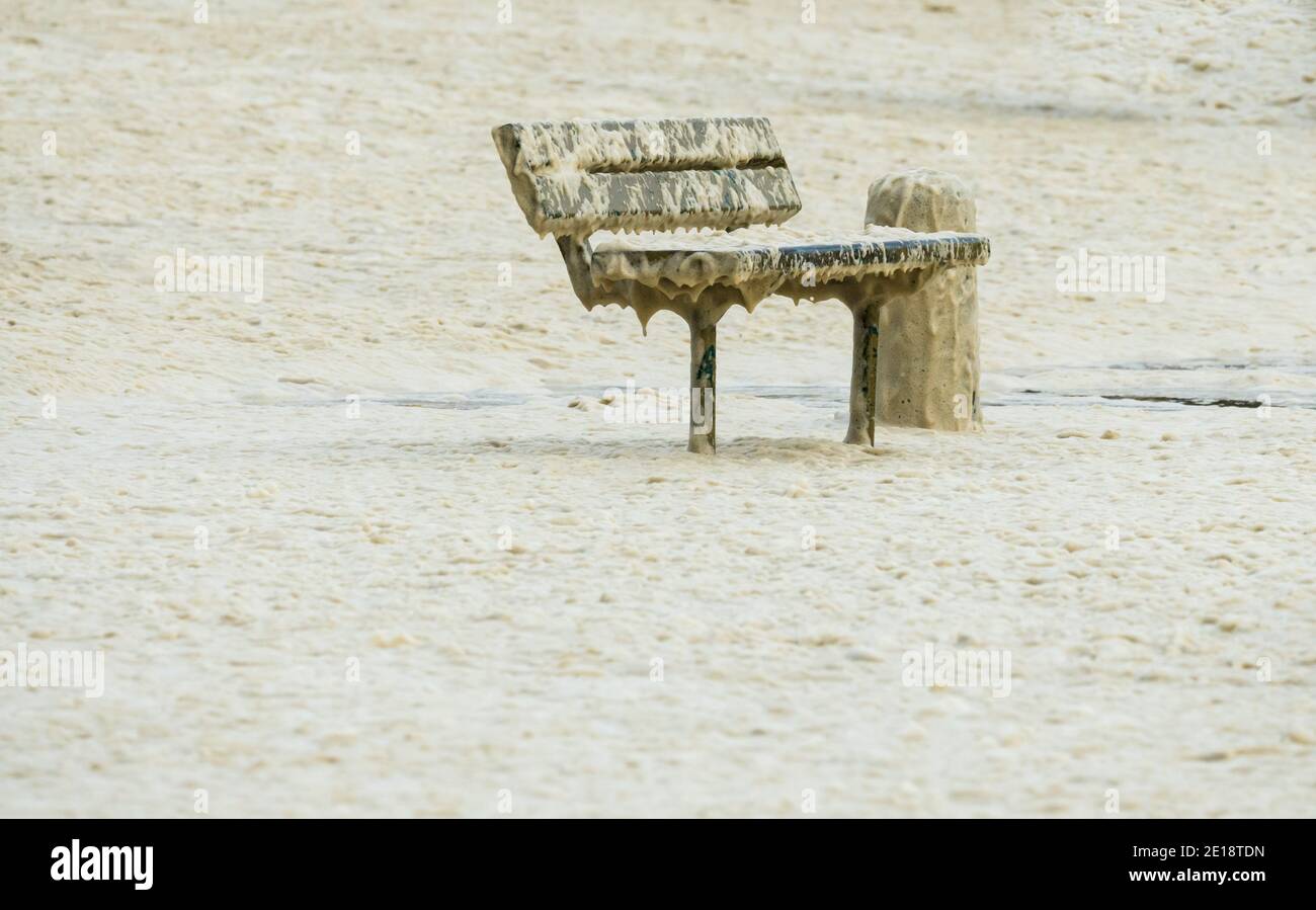 Banc à l'extérieur entouré de mousse de mer ou d'émanations lors d'une tempête côtière d'hiver au Cap, en Afrique du Sud Banque D'Images