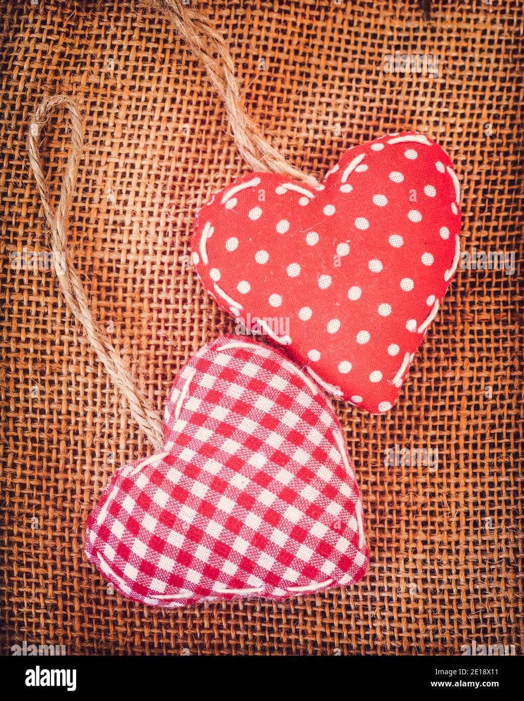 Deux coeurs en tissu rouge sur fond de toile rustique vintage Banque D'Images