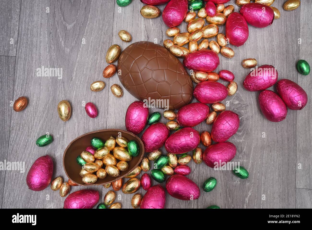 Pile ou groupe de plusieurs couleurs et différentes tailles d'oeufs de pâques au chocolat enveloppés de papier d'aluminium coloré dans le rose, le rouge, l'or et le vert. Grandes moitiés d'un bro Banque D'Images