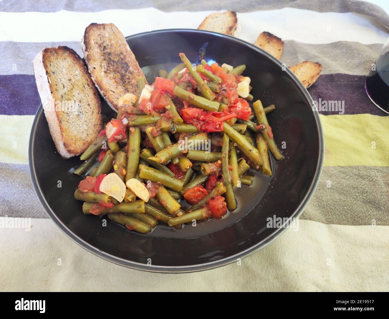 Haricots verts en sauce tomate, pain grillé et un verre de vin Banque D'Images