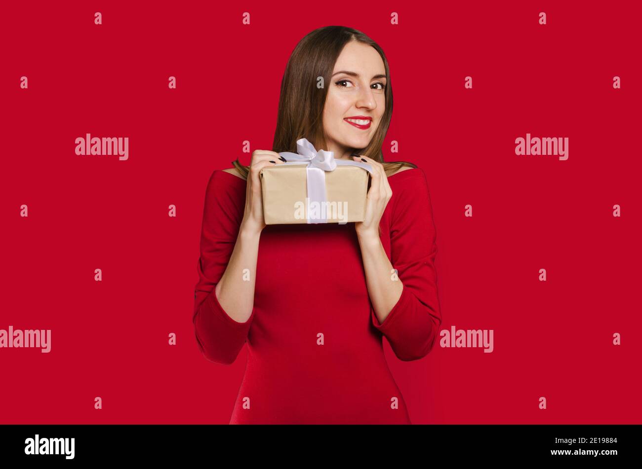 Belle fille heureuse tenant boîte cadeau dans la robe rouge. Concept de la Saint-Valentin Banque D'Images